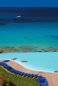 圣特雷莎加卢拉COLONNA GRAND HOTEL CAPO TESTA, a Colonna Luxury Beach Hotel, Santa Teresa Sardegna的一片蓝伞海滩和大海