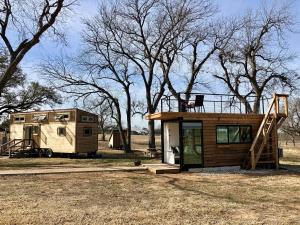 韦科Montana Escape Elegant Tiny House in Waco Near Magnolia的田野里的一个小房子和一辆拖车