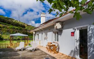 拉奥罗塔瓦Estudio rural - Nature & Relax的白色的房子,设有配有椅子和桌子的庭院