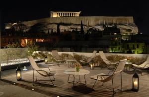 雅典海洛狄恩酒店的一群椅子和一张桌子在晚上的庭院里