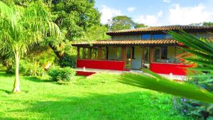 瓦尔任博尼塔Praia da Crioula的绿色庭院中的红色和黄色房子