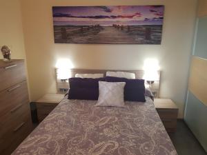 圣巴托洛梅Vista al mar playa del aguila!的一间卧室配有一张带两盏灯的床,墙上挂有一幅画