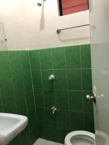 马拉帕斯加Edem Tourist Inn Malapascua的绿色瓷砖浴室设有卫生间和水槽