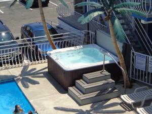 怀尔德伍德后甲板汽车旅馆的棕榈树游泳池旁的热水浴池
