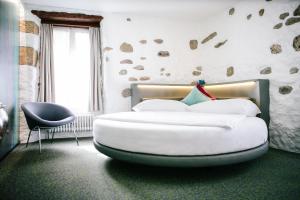 穆尔滕穆尔滕霍夫＆克朗酒店的卧室配有一张白色大床和一把椅子