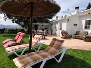 阿尔考辛Casa Molina的庭院配有两把椅子和一把遮阳伞