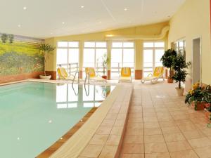 奥斯赛拜-屈隆斯博恩Pension Zum Riedensee的一座设有黄色椅子的酒店游泳池