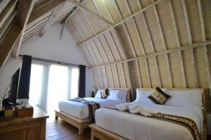 龙目岛库塔Lavella Villas Kuta Lombok的一间卧室设有两张床和大窗户