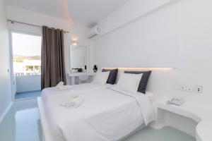 提诺斯拜占庭市酒店的白色的卧室设有一张白色大床和一个窗户。