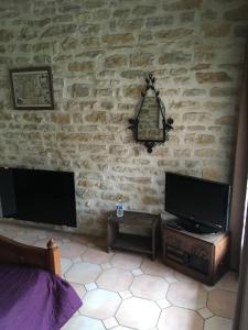 Villaines-les-PrévôtesLa Luterne的一间卧室设有石墙、电视和桌子