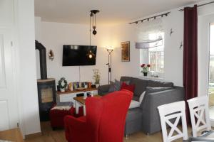伯尔格伦德-雷特维施Reethaus Casa Baltica的客厅配有灰色的沙发和红色的椅子