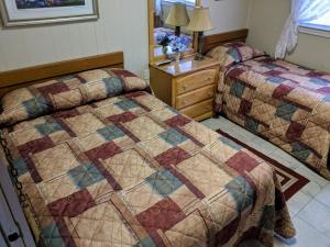 怀尔德伍德Oakview Hotel的一间卧室配有两张床和一个带被子的梳妆台。