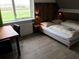 弗劳温普尔德霍夫斯泰德艾尔泽努德度假屋的一间卧室配有一张床、一张桌子和两个窗户