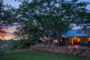 巴卢莱自然保护区Sangasava Safari Lodge的一座石墙和一棵树的房子