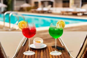 阿比让ONOMO Hotel Abidjan的三个酒杯坐在桌旁的游泳池边