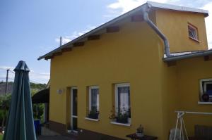 PoštornáU Klárinky的一座黄色的房子,上面有一把绿色的伞和一个建筑
