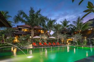 乌布Bliss Ubud Spa Resort的一座带椅子的度假游泳池以及一座建筑