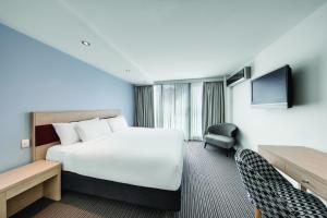 悉尼Central Studio Hotel Sydney的一间酒店客房,配有一张床和一台电视