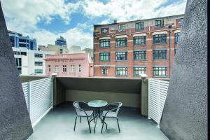 悉尼Central Studio Hotel Sydney的阳台配有两把椅子和一张桌子,公寓大楼