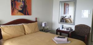 马盖特The Homestead Margate - South Africa的卧室配有一张床,墙上挂有绘画作品