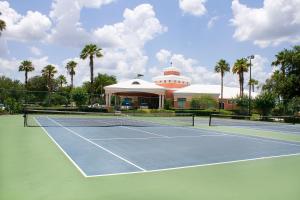 奥兰多埃克斯瑞度假胜地夏日海湾奥兰多酒店的一座棕榈树建筑前的网球场