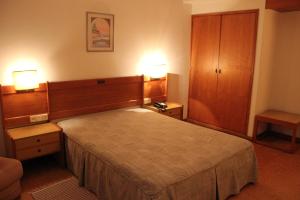 普拉多博玛苏克索酒店的一间卧室设有一张大床和两个床头柜