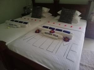 阿鲁特伽马Methira Villa的两张带白色床单和鲜花的床