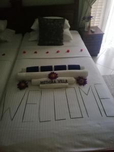 阿鲁特伽马Methira Villa的两张带白色床单的床,上面有国家别墅标志