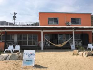 高松Megijima Island Guesthouse & cafe Megino的前面设有吊床的建筑