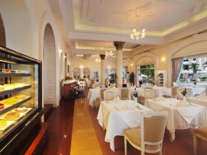 胡志明市西贡大陆酒店的一间设有白色桌椅的餐厅以及一间自助餐