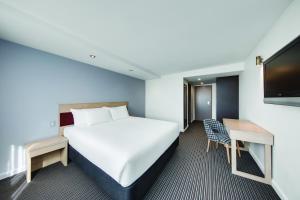 悉尼Central Studio Hotel Sydney的一间酒店客房,配有一张床和一台电视