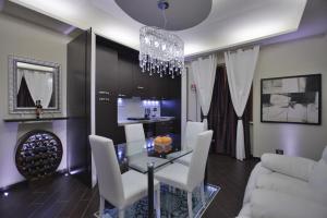 锡尼亚欧罗之家舒适公寓的一间设有玻璃桌和白色椅子的用餐室