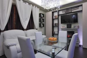 锡尼亚欧罗之家舒适公寓的一间设有玻璃桌和白色椅子的用餐室