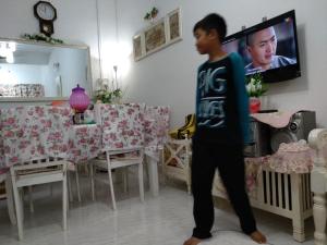 玻璃市港口Anis Homestay Kuala Perlis的站在客厅看电视的男孩