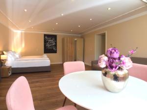 波茨坦Amaroo - Apartments Potsdam “Alexandrowka”的配有桌子、粉红色椅子和床的房间