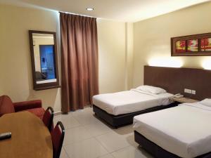 马六甲淡边中心酒店的酒店客房设有两张床和一张桌子。
