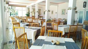新马克立尼柔斯酒店的用餐室配有白色的桌子和木椅