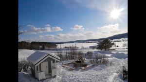 恩舍尔兹维克Villa utanför Örnsköldsvik, Höga Kusten的雪中的小建筑,太阳在后面