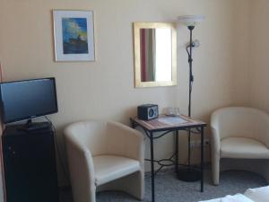 瓦尔内明德Landhotel Ostseetraum & Fewo的一间设有两把椅子和一张桌子及电视的房间