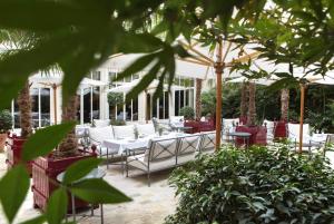 巴黎La Réserve Paris Hotel & Spa的庭院配有白色的桌椅和树木