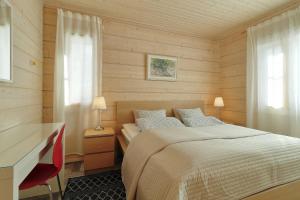 JaalaVilla Maria Cottages的一间卧室配有一张床和一张带红色椅子的书桌