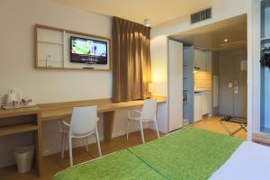 里昂Appart hôtel Q7 Lodge Lyon 7的一间卧室配有一张桌子、两把椅子和一台电视