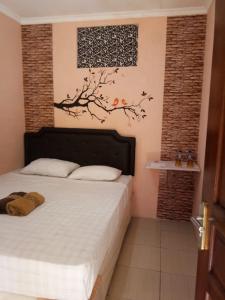 日惹恩达利艾安格维耶旅馆的卧室配有一张床铺,墙上挂着一棵树