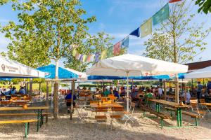 Au an der Donau多瑙河河畔露营地及旅馆的坐在餐厅桌子和遮阳伞下的人