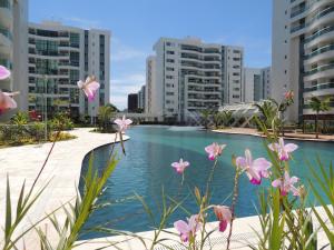 巴西利亚Apartamento 2 quartos Living Park Sul的一座游泳池,在一些建筑前有粉红色的花朵