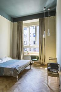 米兰卡萨贝斯青旅的卧室配有床、椅子和窗户。