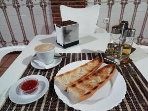 TalaveruelaHostal Zaguan的一张桌子,上面放着一盘面包和一杯咖啡