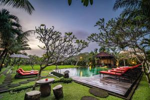 乌布Bliss Ubud Spa Resort的一个带红色椅子和木制甲板的游泳池