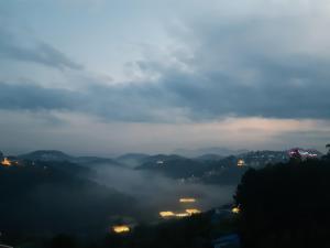 大叻Duy Hotel的享有带建筑和灯光的雾 ⁇ 山谷的景色