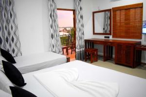 雅拉Blue Sky Hotel Yala的酒店客房设有两张床、一张书桌和一个窗户。